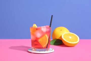 Glass of delicious Negroni cocktail and oranges on color background