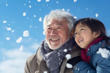 冬の青空の下で雪遊びをする日本人の祖父母と孫（雪景色・ 笑顔・家族）