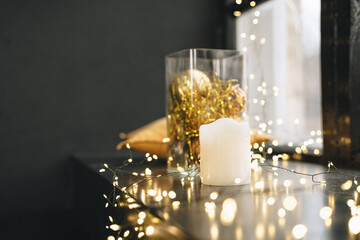 Black windowsill decorated for Christmas with golden baubles and candles