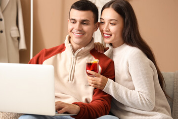 Happy couple with glasses of warm mulled wine watching movie in living room