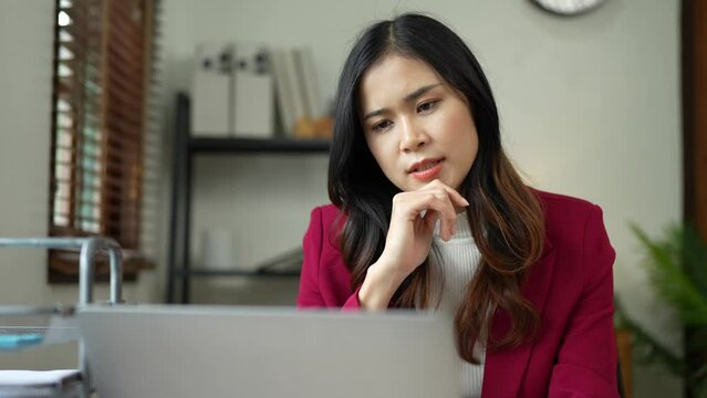 Asian female office workers are stressed while working with stacks of documents and laptops. Feeling tired, headaches, and burned out at work feeling sick Not happy in the office.