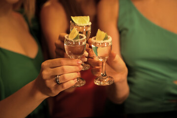 Young women with tequila shots in bar at night, closeup