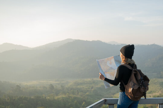 Adventurous girl navigating in with a topographic map in beautiful mountains of thailand. woman wearing hat stand alone and enjoying freedom and calm inspired travelling on background view mockup.