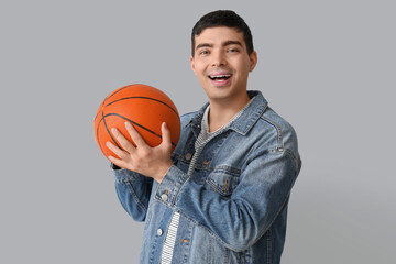 Happy young man with ball on light background