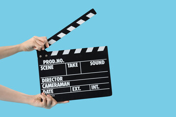 Young actress with movie clapper on blue background