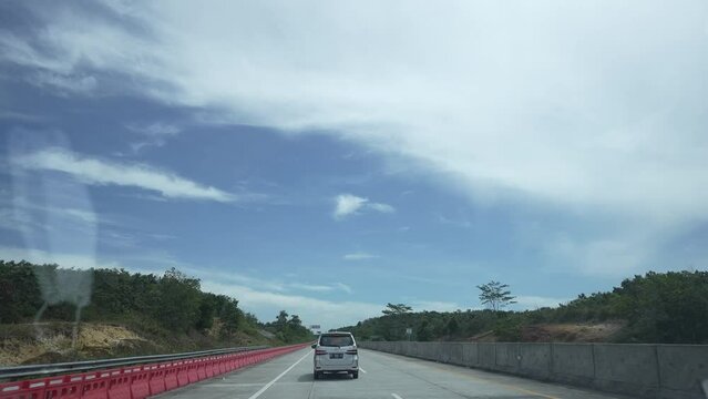 Along the toll road by car. Driving along the highway road or toll road infrastructure with blue sky and forest beside.