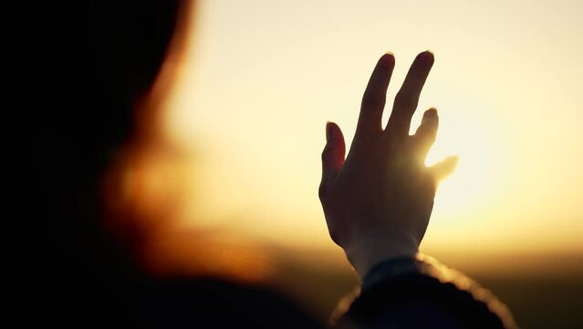 Silhouette of happy dreaming girl pulls her hand to sun.Religion helping hand. Happy girl pulls her hand.Prayer in religion.Silhouette of hand in sun.Happy girl silhouette at sunset.Freedom in nature