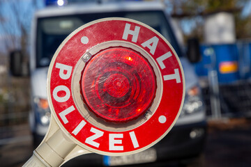 Polizeikontrolle: Nahaufnahme einer Polizeikelle mit der Aufschrift HALT POLIZEI vor einem...