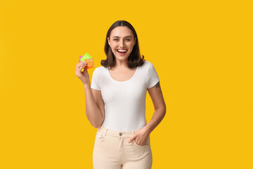 Beautiful young woman with condoms on yellow background. Safe sex concept