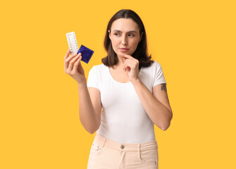 Beautiful young woman with condom and birth control pills on yellow background. Safe sex concept