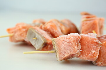 frosted salmon pieces on skewers wooden stick closeup photo