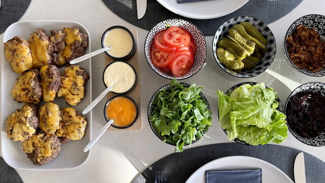 Top Shot Of Cheeseburger, Sauce And Salad Served On The Dining Table