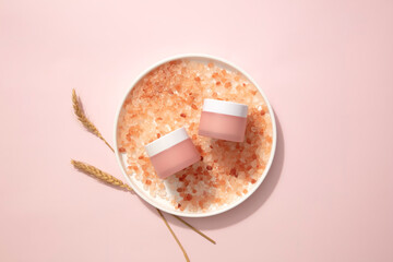 Elevate skincare regimen with jars of calming pink lotion on a plate accompanied by pink salt. Proven effective for insect bites and blisters-ideal for impactful advertising visuals.