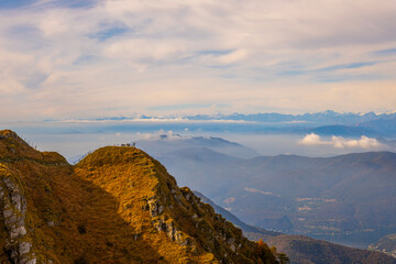 Aerial View over a Beautiful Mountainscape and a Mountain Peak with People and with Floating Clouds...