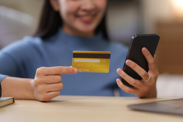Young asian woman using smartphone and credit card for online shopping at home. Asia female enjoying the convenience of online shopping from the comfort of her home.