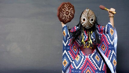 Shaman a native American Indian in a shamanic mask with a shamanic tambourine