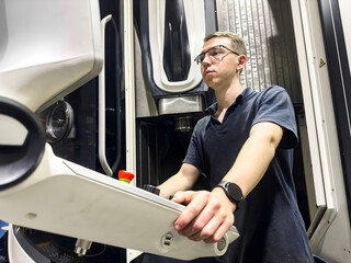 A worker examines the on-board computer of a new five-axis CNC milling machine