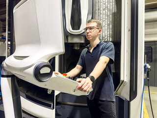Having studied the CNC milling machine from the outside, the worker takes up the on-board computer and software
