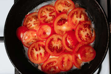 The process of cooking fish with tomatoes in a frying pan, top view
