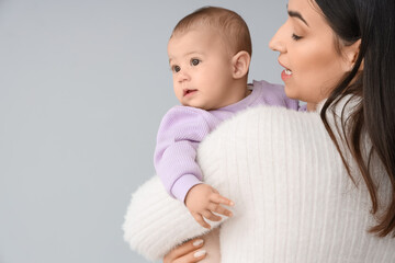 Happy mother with her little baby on light background, closeup