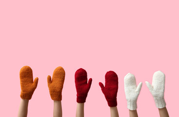 Female hands in warm knitted mittens on pink background