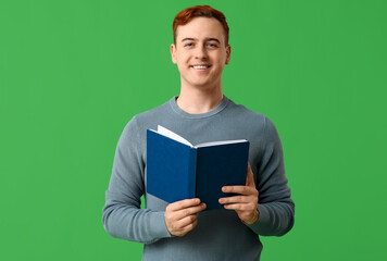 Smiling handsome man with book on green background