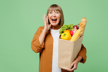 Elderly woman wears brown shirt casual clothes hold shopping paper bag with food products scream...