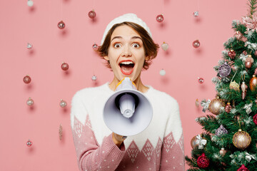 Merry young woman wear white sweater hat posing hold in hand megaphone scream announces discounts...