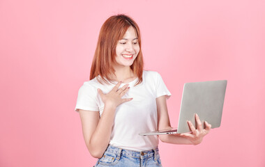 Young smiling student freelancer young asian woman using laptop for remote work, e-learning at university college, e-banking, online shopping, webinars isolated in pink background, Looking laptop.