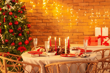 Dining table with Christmas setting and burning candles in room
