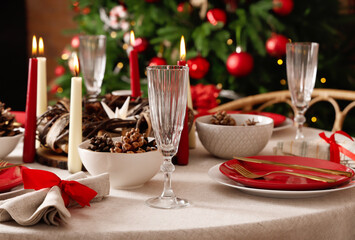 Dining table with Christmas setting and burning candles in room, closeup
