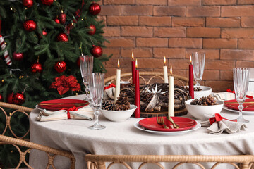 Dining table with Christmas setting and burning candles in room