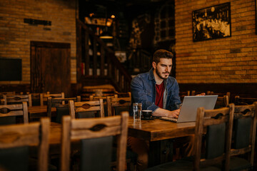 Fototapeta na wymiar Casual guy working on laptop in a cozy cafe