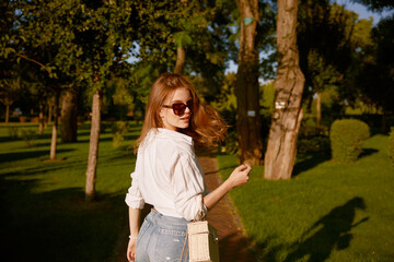 Outdoor portrait of young pretty woman walking in park at sunny day