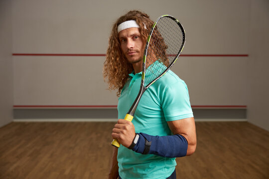 Portrait of confident male squash player standing with racket ready for game