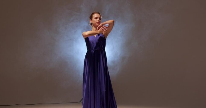 beautiful talented ballet dancer posing gracefully against gray studio background. Concept of activity. Slow motion magic dance
