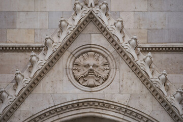 Bas relief of a face turned to stone on a facade of the Hungarian Parliament Building (Hungarian: Országház). Budapest, Hungary - 7 May, 2019