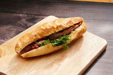 Banh Mi Heo Quay.Vietnamese bread with roasted pork and fresh herbs as scallions, coriander, carrot, cucumber, chilli