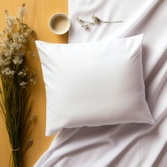 A white mockup pillow lies on a white fabric, next to it are plant branches and a cup of coffee.
