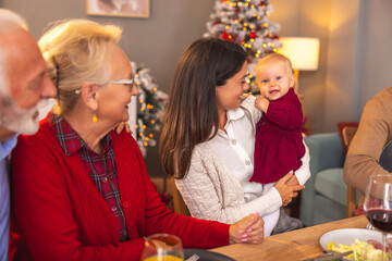 Senior couple having Christmas dinner with daughter and granddaughter