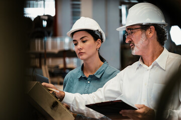 Factory manager inspecting industrial steel machinery and overseeing while supervising and...