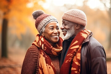 Fototapeta premium An elderly dark-skinned couple, a man and a woman, hugging in an autumn park. They look at each other with a loving gaze. Seniors dating. Relationships in old age. Love and romance.