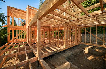 Residential wooden frame house under construction near a forest. Beginning of new construction of cozy house or cottage. The concept of modern ecological construction and architecture.