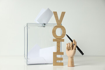 Voting box with papers, wooden letters and hand with pen on white background