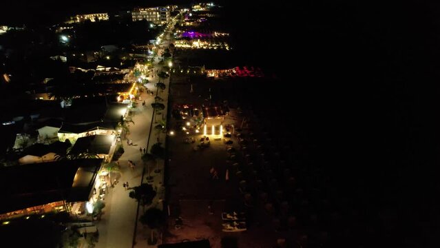 Beach Bars Aglow with Lights, Waves Gently Lapping the Dark Sea, Evoking Joyful Summer Vacation Vibes by Night in Dhermi