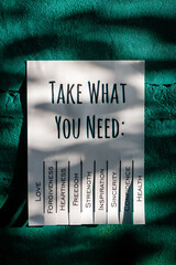 White tear-off stub note with text 'Take what you need' on emerald wall.