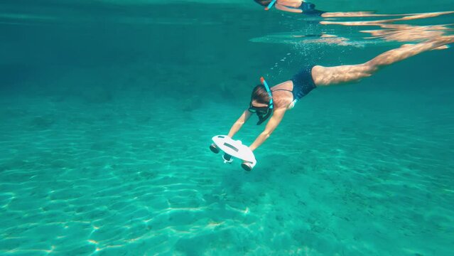 Woman using underwater scooter for diving. Modern sea scooter, modern technology concept.
