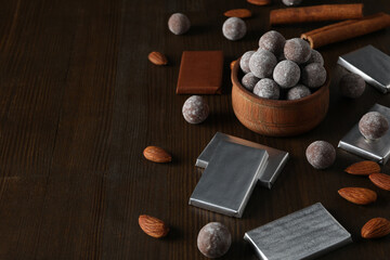 Chocolate balls in a wooden bowl with chocolate bars and almonds