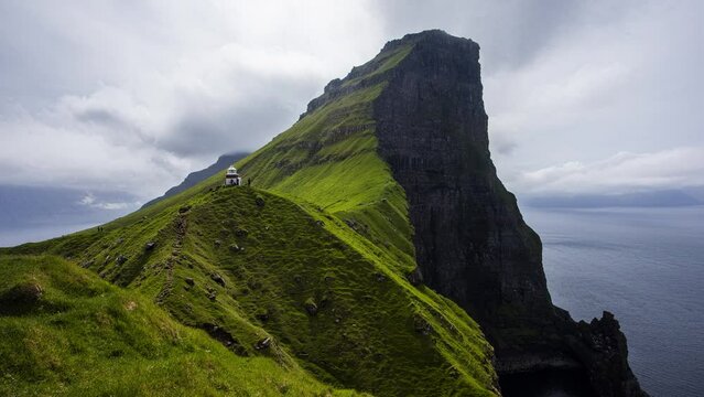 Time lapse of Kallur lighthouse on green hills of Kalsoy island, Faroe islands, Denmark.