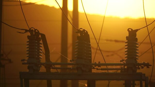 High voltage electric transformer station and distribution network at sunset. Power transmission lines on supports with ceramic insulators and transformers at large electrical distribution substation